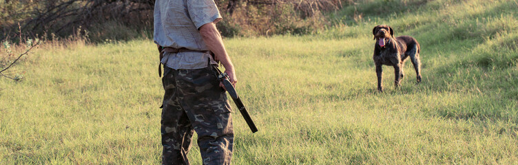 A man with a gun in his hands and an green vest on a pheasant hunt in a wooded area in cloudy...