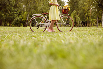 Fototapeta na wymiar Crop woman with retro bike on lawn