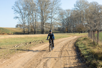 Cyclist in pants and fleece jacket on a modern carbon hardtail bike with an air suspension fork rides off-road.