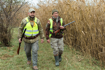 Hunting period, autumn season open. A hunter with a gun in his hands in hunting clothes in the...