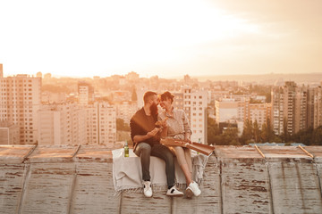 Happy young couple eating pizza on roof