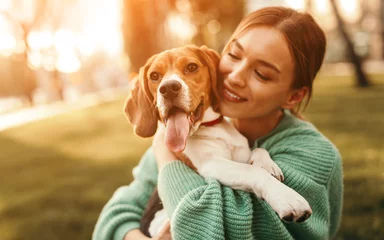 Tuinposter Happy woman embracing beagle dog in park © kegfire