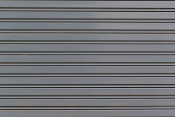 Metallic roll up door. Old Steel rolling shutter background. Metal security shutters protecting a small shop.