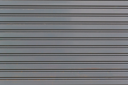 Metallic roll up door. Old Steel rolling shutter background. Metal security shutters protecting a small shop.