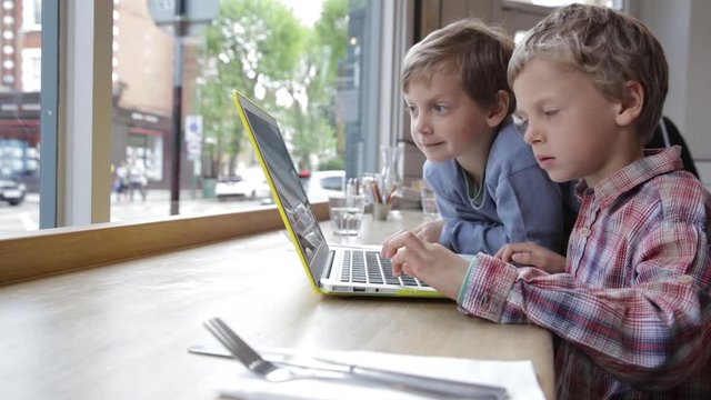 Two boys playing educational game on laptop
