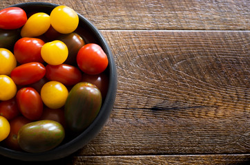 Bowl of cherry tomatoes on wooden table with copyspace