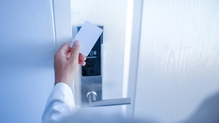 Hand holding key card using electronic card for access hotel room.