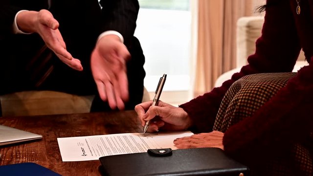 契約書類にサインする高齢女性
