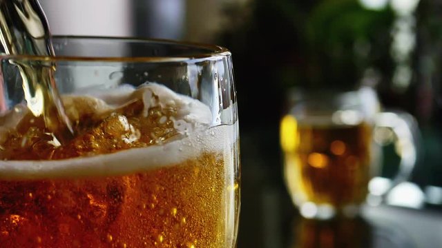 Beer is pouring into beer mug in close up slow motion and is overflowing