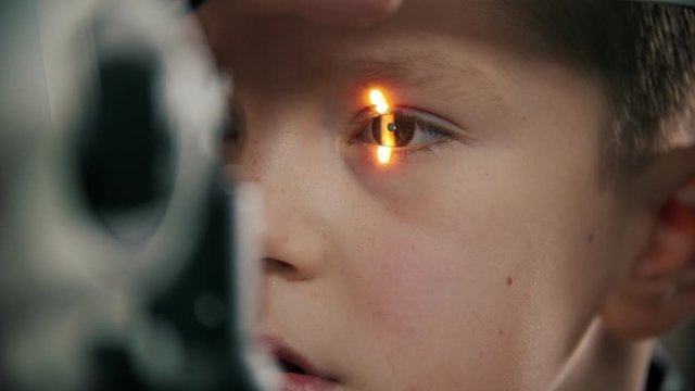 A little boy having a treatment in eye clinic - shine light in the eye