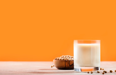 Soy milk and soy bean on orange background. Non-dairy milk concept. Vegan Drink. Copy space