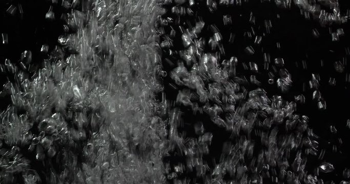 Macro shot of air bubbles rising rapidly in water on a black background isolated. Boiling water. World water day. 4K slow motion 50 fps