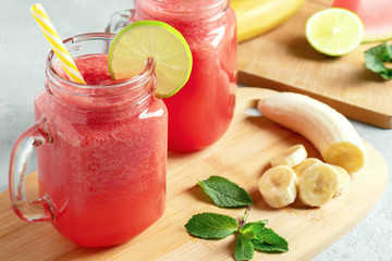 Watermelon smoothie with banana, lime and mint in mug jars on a cutting board. Healthy eating concept