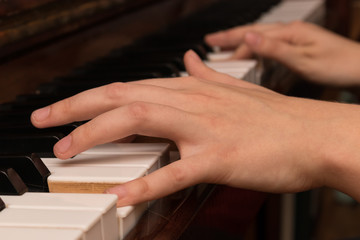 Hands of a girl playing the piano close-up