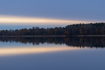 Serene landscape. Sunset on the lake, calm water surface, symmetrical reflection