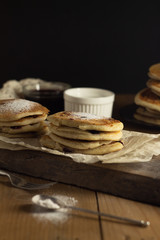 Stacks of gluten-free pancakes with a sprinkle of powdered sugar on a dark background