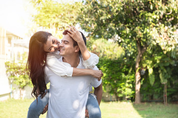 Obraz premium Couple in love asian woman riding on back of caucasian man at park,Romantic and enjoying in moment of happiness time,Happy and smiling,Positive thinking