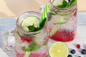 Homemade cold summer cocktail with mineral water, mint, lime, berry juice and fresh berries
