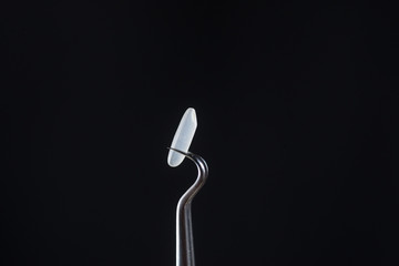 Closeup one tweezers clamp a grain of rice isolated on black background.