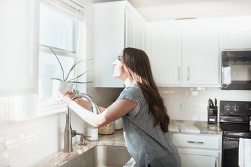 Women holding indoor plant in a white kitchen