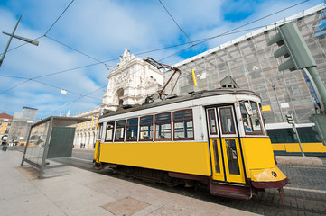 Yellow electric tram on old streets and colorful buildings of Lisbon, Portugal, popular tourist attraction