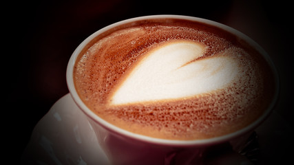 Cappuccino coffee heart shape in white cup.