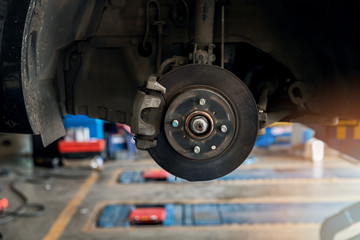 Maintaining car disc brake in process of new tire replacement at repair service station.