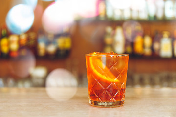 Glass of tasty alcoholic negroni cocktail with orange slice on bar stand. Festive concept. with...