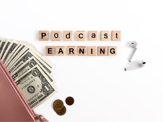 Podcast Earning words on wooden letters. White background with some money. Concept f making money by Podcast.