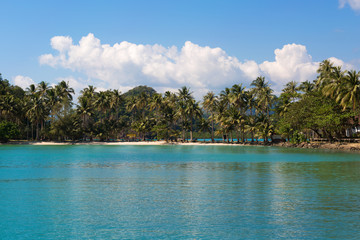 Tropical island sand beach on the sea. Blue sky with clouds.