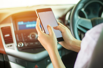 Asian women are driving cars and using a smartphone on the road.