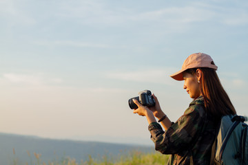 women asian with backpack taking a photo on view at sunrise seaside mountain peak