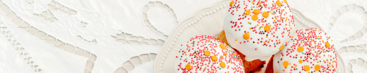 Happy Easter cake with sprinkles on white glaze. Easter cake on rustic wooden board. Horizontal banner for website design. Selective focus, free text space.