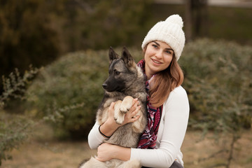 The owner is a beautiful girl holding her Keeshond dog in her arms, looking at each other and smiling. Place for the inscription. Concept: love between dog and owner. Protection of animals.