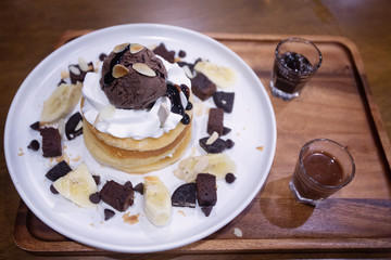 Pancakes with bananas and brownies topped with whipped cream and chocolate ice cream