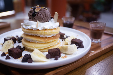 Pancakes with bananas and brownies topped with whipped cream and chocolate ice cream