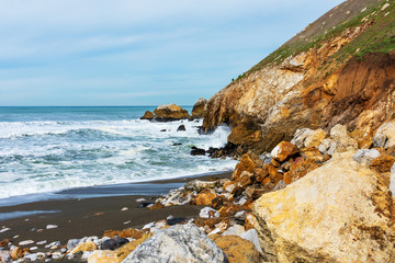 Ocean waves crash on empty sandy and rocky beach