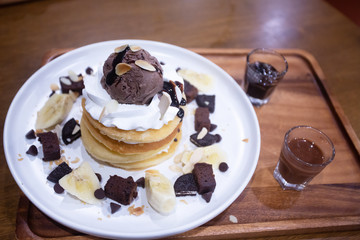 Pancakes with bananas and brownies topped with whipped cream and chocolate ice cream
