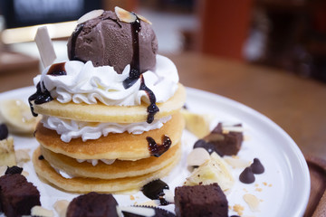 Pancakes with bananas and brownies topped with whipped cream and chocolate ice cream