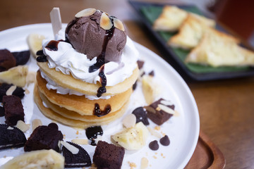 Pancakes with bananas and brownies topped with whipped cream and chocolate ice cream