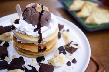 Pancakes with bananas and brownies topped with whipped cream and chocolate ice cream