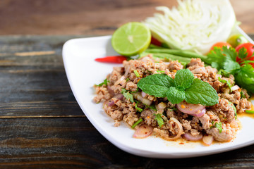 Thai food, spicy minced pork salad (Larb Moo) on white dish	