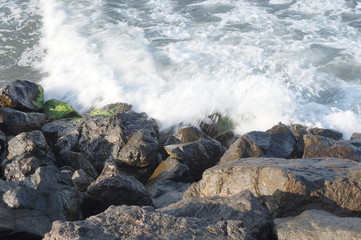Stones on the black sea and breaking wave in blur at a long exposure.