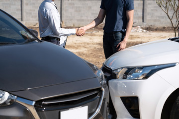 Fototapeta na wymiar Insurance Agent and customer shaking hands after agreement about in insurance claim, assessed examining car crash, checking and signing on report claim form process after accident collision