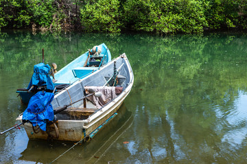 Old metal fishing boat floating on the river with green tree at the background, transportation concept, travel by boat, outdoor day light