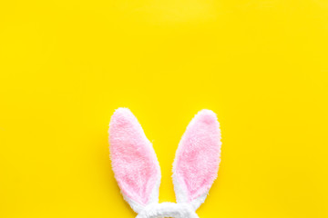 Easter bunny concept. Toy rabbit's ears on yellow background top-down copy space
