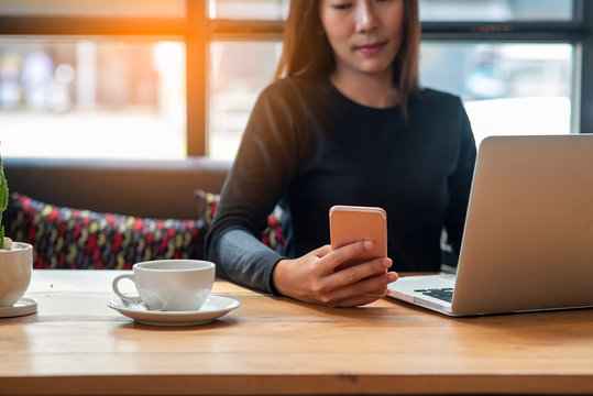 Lifestyle of entrepreneur share to social media (twitter) and using smart phone via 5g internet to post her blog.Young blogger searching on digital device and typing report by laptop  in coffee shop.