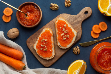 Sandwiches with carrot jam and nuts on a cutting board on a dark background