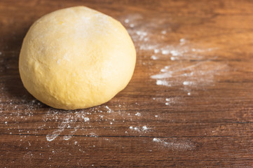 light yellow bread dough on wooden table top surface with dusting flour.	