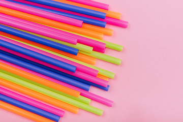 colored tubules for juice and cocktails on pink background. Colorful drink straws. straw, plastic free, reusable plastic drinking background, plastic free. Plastic pollution concept.